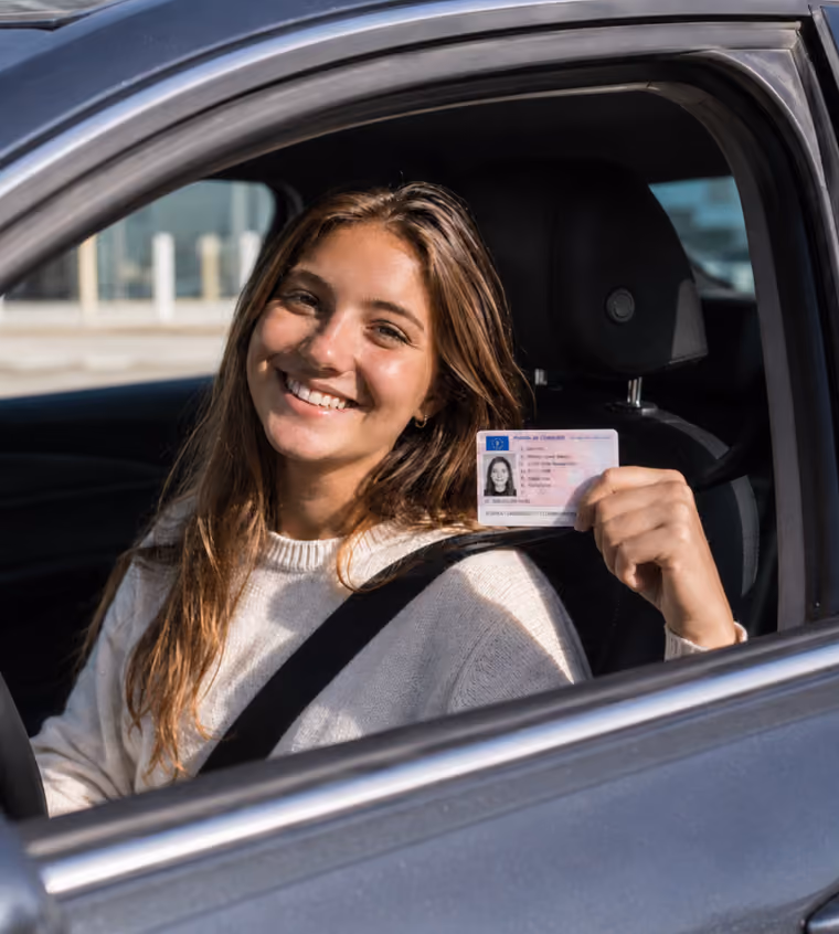 Jeune conductrice souriante montrant son permis de conduire