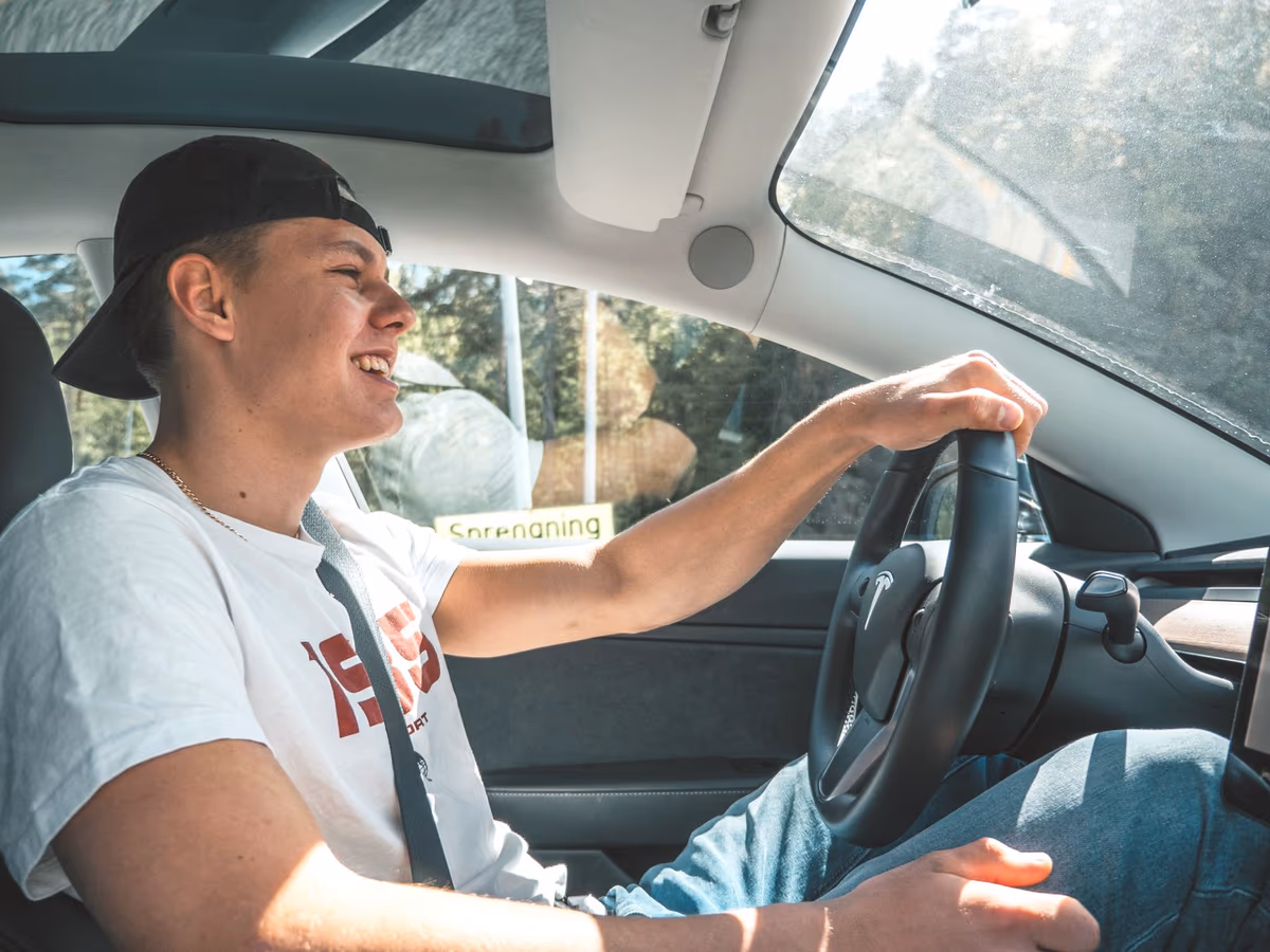Un jeune conducteur souriant, ceinture attachée, au volant de sa voiture