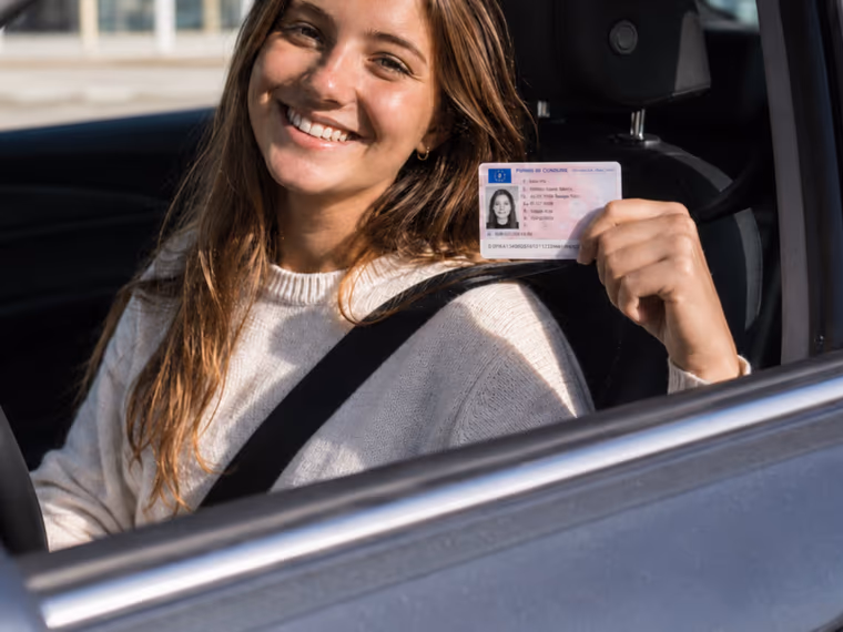 Une jeune conductrice montre fièrement son permis de conduire