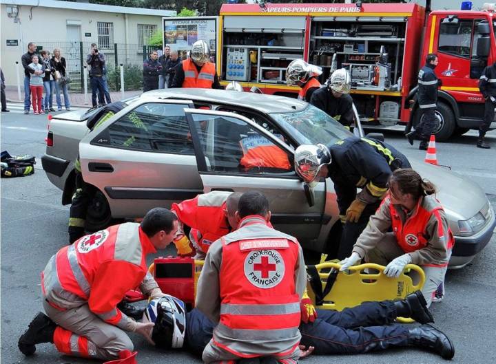 Secouristes de la Croix-Rouge et pompiers portent secours à une victime près d'une voiture