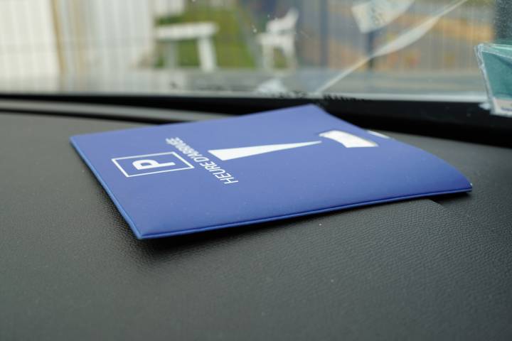 Disque de stationnement bleu posé sur le tableau de bord derrière le pare-brise