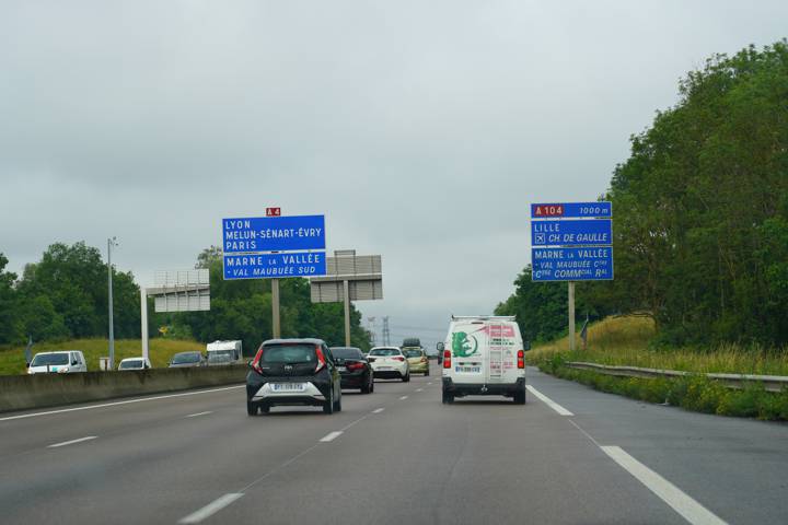Autoroute avec panneaux de direction bleus vers Lyon et A104, plusieurs véhicules circulent