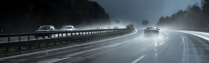 Autoroute sous une forte pluie, chaussée mouillée et projections d'eau derrière les véhicules