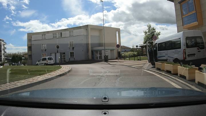 Sortie de zone résidentielle, un minibus et un utilitaire stationnés à droite