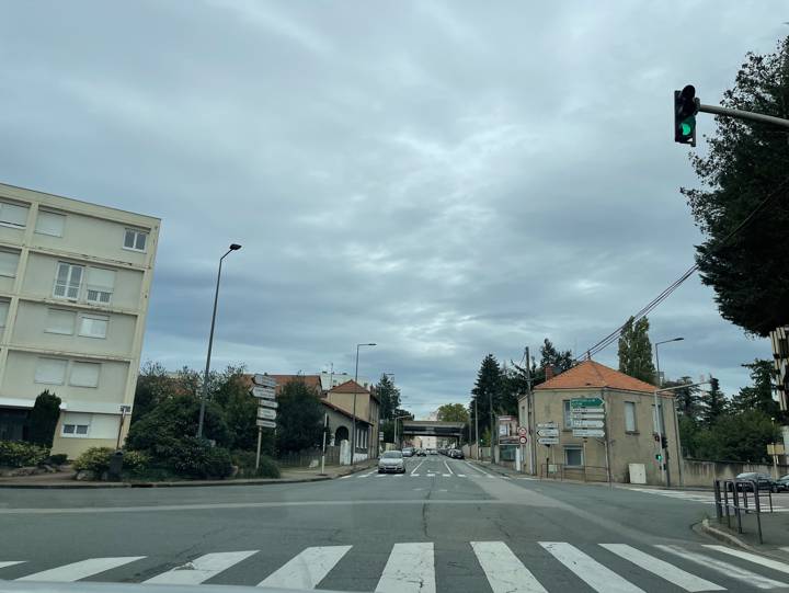 Intersection en ville au feu vert, une voiture grise arrive en sens inverse