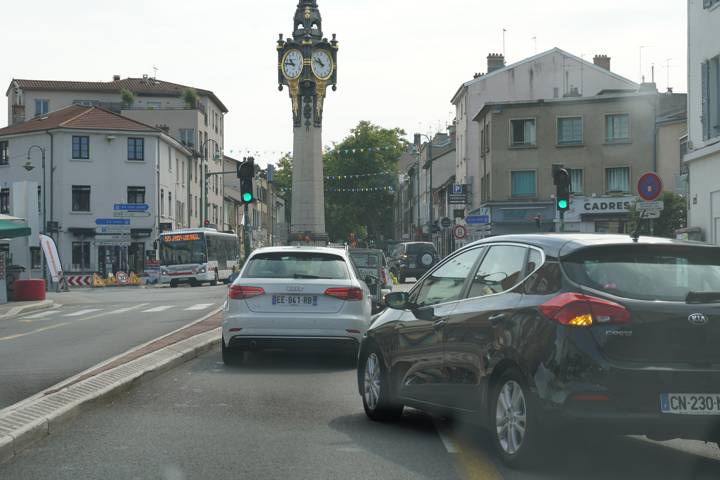 Centre-ville encombré, voitures et bus à l'arrêt près d'une tour-horloge