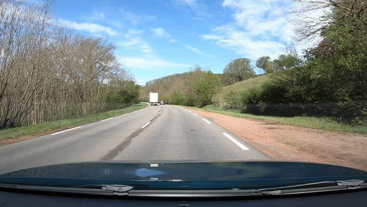 Vue conducteur sur une route de campagne, un poids lourd dépasse au loin près d'un virage