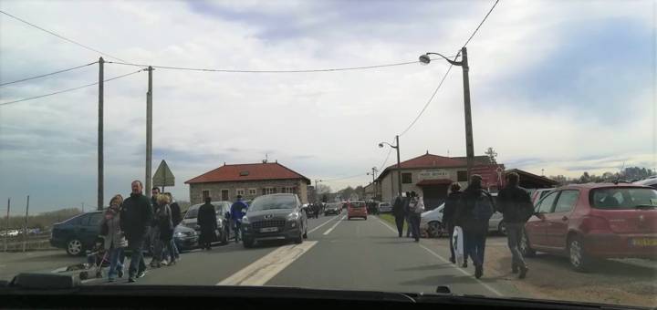 De nombreux piétons marchent au bord et traversent la route, parmi les voitures