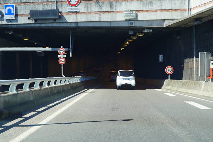 Entrée d'un tunnel routier avec panneaux de limitation à 70 km/h et interdiction de dépasser