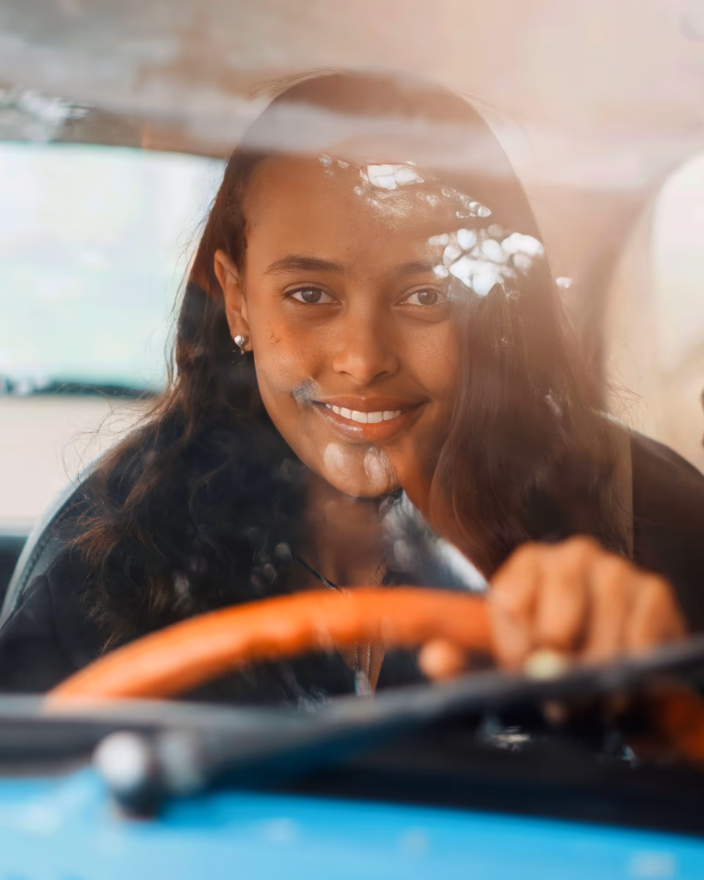 Une jeune conductrice sereine et souriante au volant, en toute confiance
